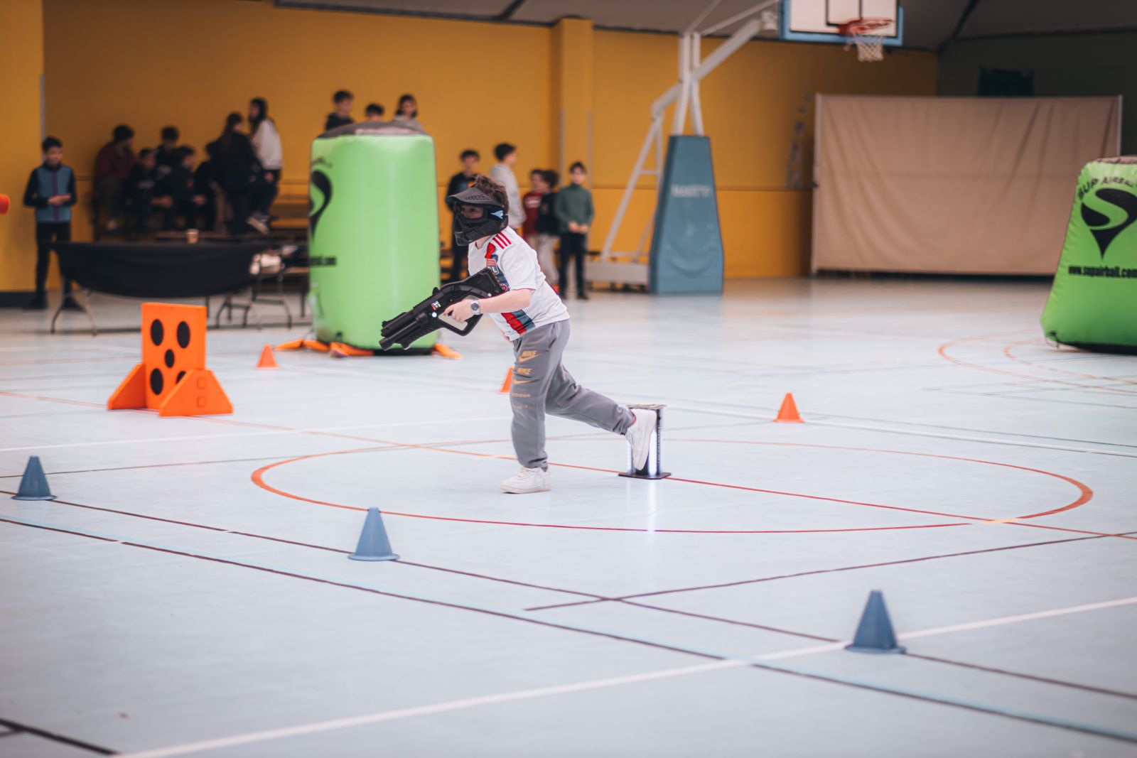 Arène laser game indoor — joueur en action avec pistolet laser et obstacles